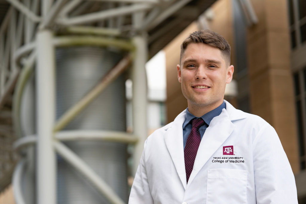 man standing next to building and wearing College of Medicine lab coat