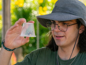 A student holding a plastic container with a bug trapped inside