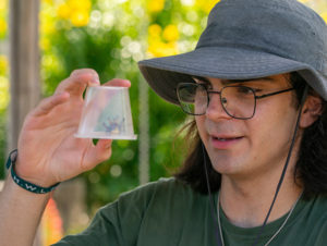 A student holding a plastic container with a bug trapped inside.