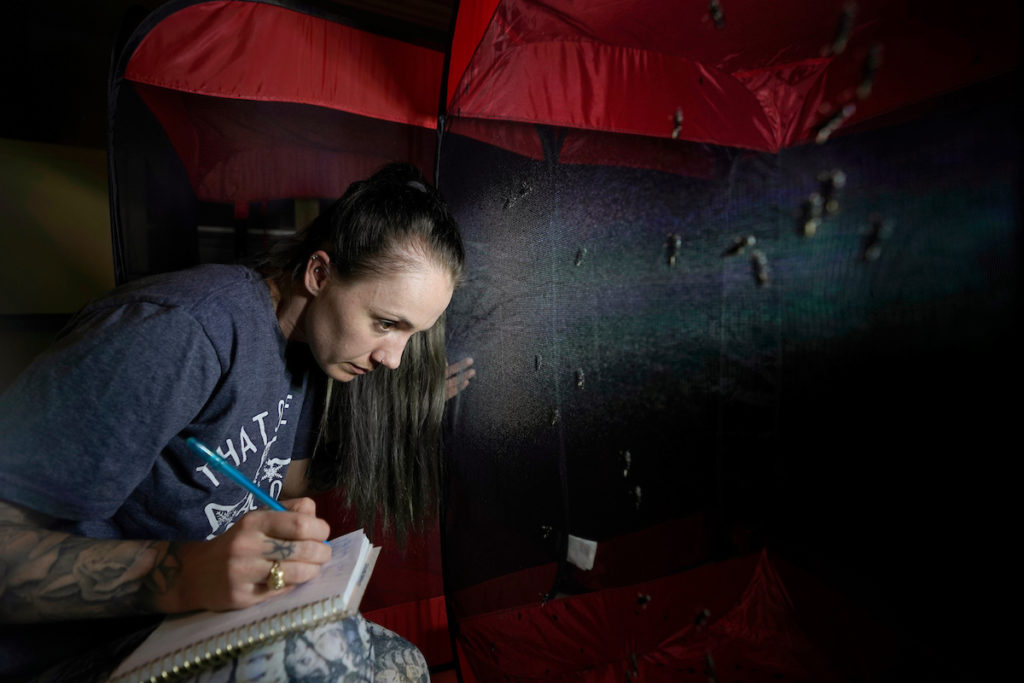 Girl looking at bugs while taking notes on a notebook while wearing her Aggie ring.