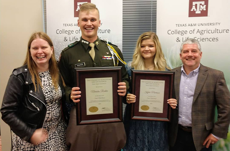 Students standing in front of banners after an awards ceremony