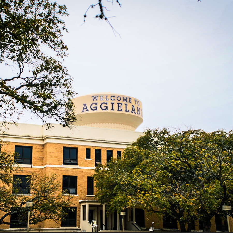 Welcome to Aggieland water tower and building surrounded by trees on Texas A&M University campus